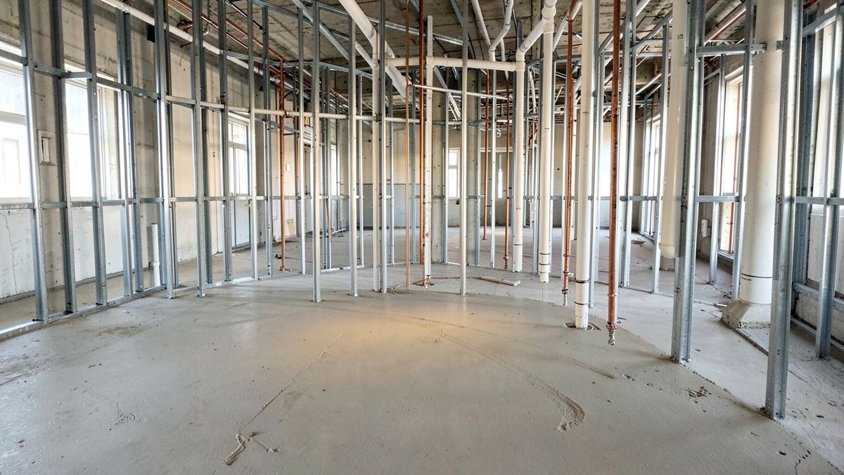 Interior of a commercial building under construction with metal studs and new PVC and copper plumbing rough-in